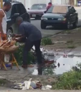 Vendedor recoge chicharrones del suelo y los lava con aguas negras de un contén