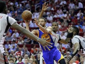 Stephen Curry, de los Warriors de Golden State, envía un pase entre Clint Capela, Trevor Ariza (1) y James Harden (13), de los Rockets de Houston, durante el encuentro del martes 28 de marzo de 2017 (AP Foto/Michael Wyke)