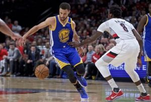 El jugador de los Warriors de Golden State Stephen Curry, a la izquierda, bota a su espalda para eludir al jugador de los Trail Blazers de Portland Al-Farouq Aminu en la primera mitad del Juego 4 de primera ronda de playoffs de la NBA, el lunes 24 de abril de 2017, en Portland, Oregón. (AP Foto/Craig Mitchelldyer)