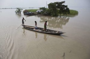 Unas personas navegan por zonas inundadas debido a las fuertes lluvias en Pokoria, en el noroeste de India, el lunes 14 de agosto de 2017. Las lluvias han causado decenas de muertos y desplazado a millones de personas en varios países de Asia. (AP Foto/Anupam Nath)